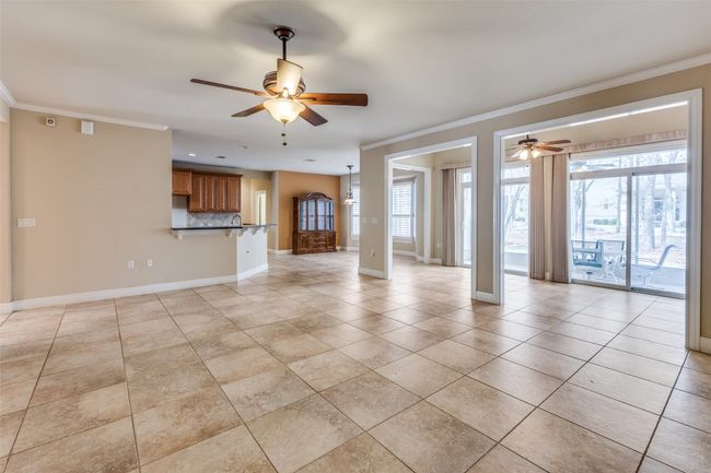 Unfurnished living room with baseboards, light tile patterned floors, ornamental molding, and a ceiling fan | Image 4