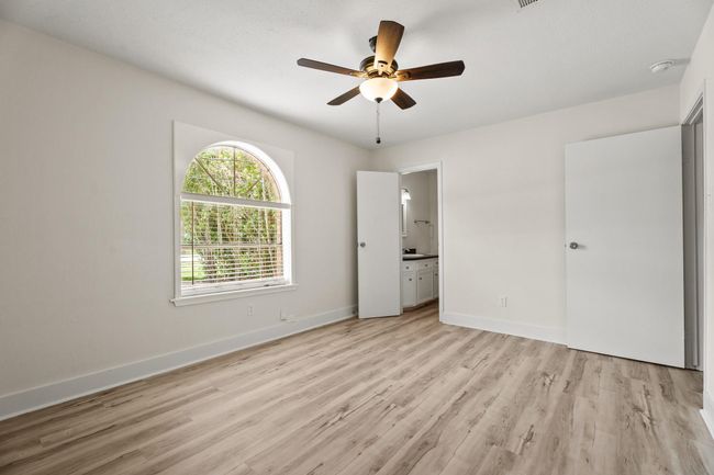 The primary bedroom features a new ceiling fan, all new paint and baseboards, and an en-suite half bath. Through the bathroom, you will find your walk in closet. | Image 7
