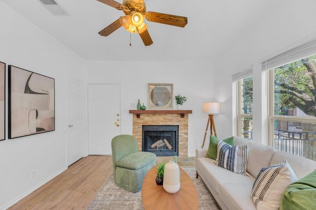 Living room featuring wood finished floors, a fireplace with raised hearth, and ceiling fan | Image 6