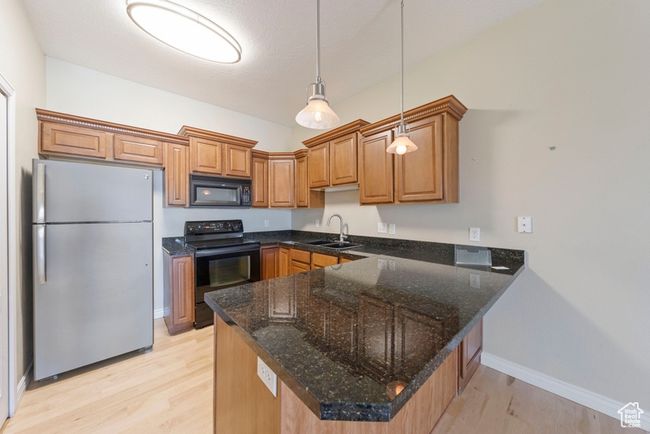 Kitchen with black appliances, a sink, light wood-style floors, a peninsula, and pendant lighting | Image 4