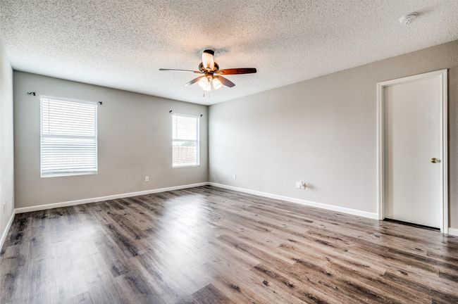 Unfurnished room featuring a ceiling fan, a textured ceiling, wood finished floors, a smoke detector, and baseboards | Image 13