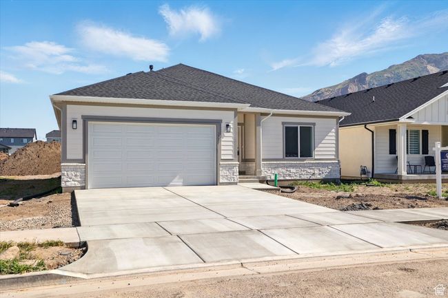 Single story home with driveway, an attached garage, a mountain view, stone siding, and a porch | Image 33