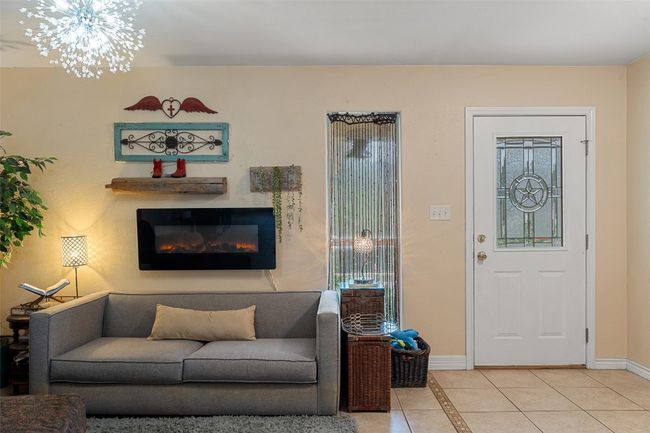 Living area with light tile patterned flooring, baseboards, plenty of natural light, and a glass covered fireplace | Image 6