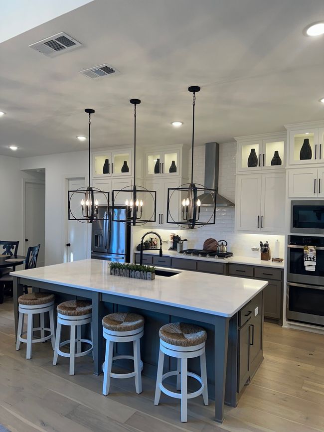 Kitchen featuring refrigerator, white cabinetry, light countertops, a large island, and glass insert cabinets | Image 16