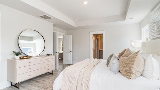 Bedroom with light wood-style floors, a raised ceiling, baseboards, and ensuite bath | Image 17