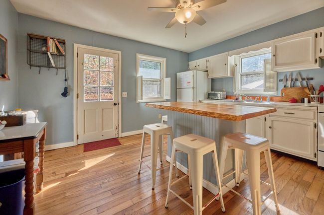 Kitchen featuring light wood finished floors, a healthy amount of sunlight, a ceiling fan, and freestanding refrigerator | Image 6