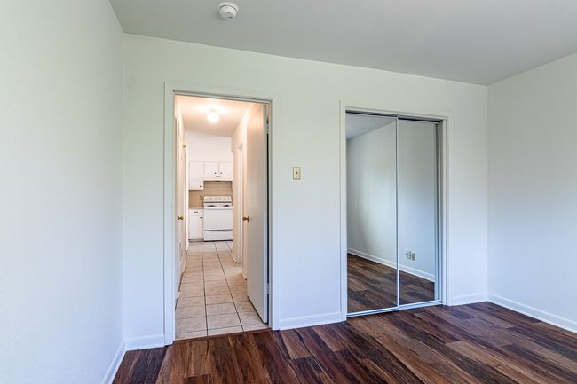 1214 Hunt - Bedroom with laminate flooring and mirror doors on closet | Image 13