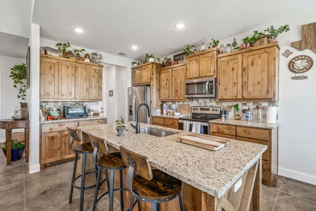 Kitchen featuring stainless steel appliances, a sink, baseboards, backsplash, and a kitchen bar | Image 8