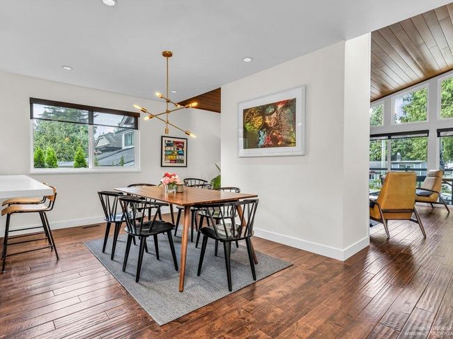 Spacious dining room with stylish lighting, space for a large table, a south facing window inviting tons of southern natural light to mingle with the western light from the adjacent living room & eastern light from the solarium and kitchen. | Image 15