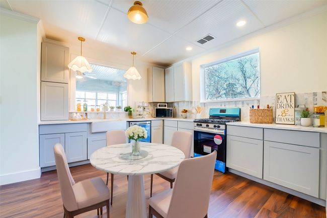 Kitchen featuring stainless steel range with gas cooktop, sink, dishwashing machine, backsplash, and hanging light fixtures | Image 6