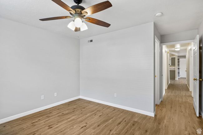 Spare room with light wood-type flooring, baseboards, a ceiling fan, and a smoke detector | Image 18