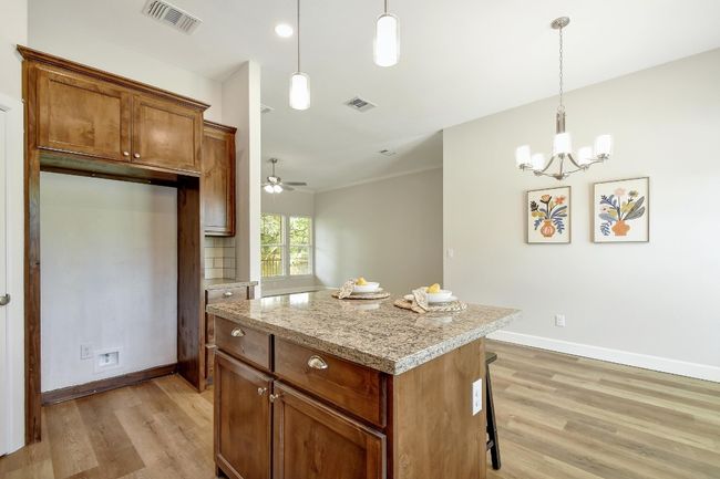 Kitchen featuring light wood-type flooring, a center island, a chandelier, and hanging light fixtures | Image 11
