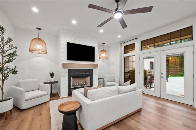 Cozy and chic, the living room features a whitewashed brick fireplace, custom wood mantel, and oversized windows that bring the outdoors in. | Image 19