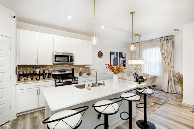 kitchen with appliances with stainless steel finishes, backsplash, a kitchen breakfast bar, and a sink | Image 8