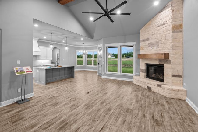 Unfurnished living room with a fireplace, ceiling fan, high vaulted ceiling, light wood-type flooring, and recessed lighting | Image 7