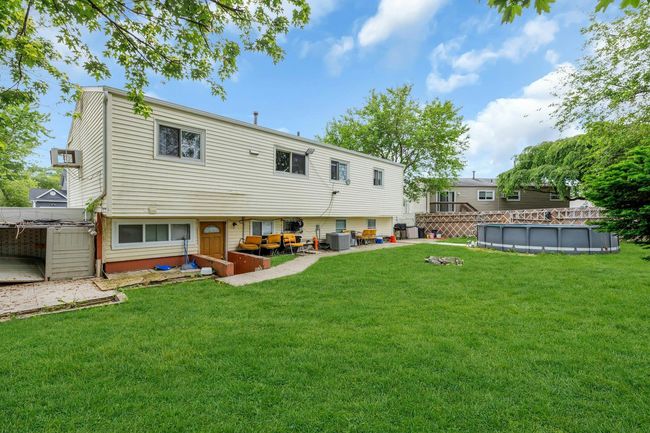 Rear view of property with a yard, an outdoor pool, a patio area, and central air condition unit | Image 13