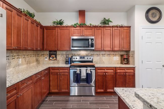 Kitchen with decorative backsplash, light stone countertops, and appliances with stainless steel finishes | Image 14