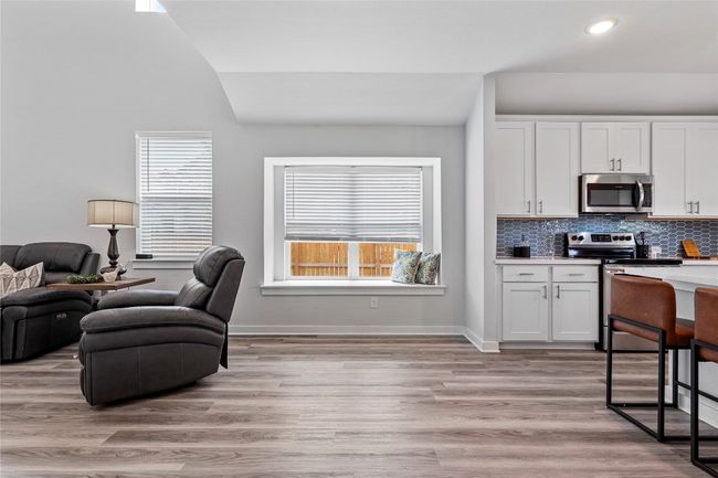 Kitchen featuring stainless steel appliances, vaulted ceiling, white cabinetry, light countertops, and backsplash | Image 17