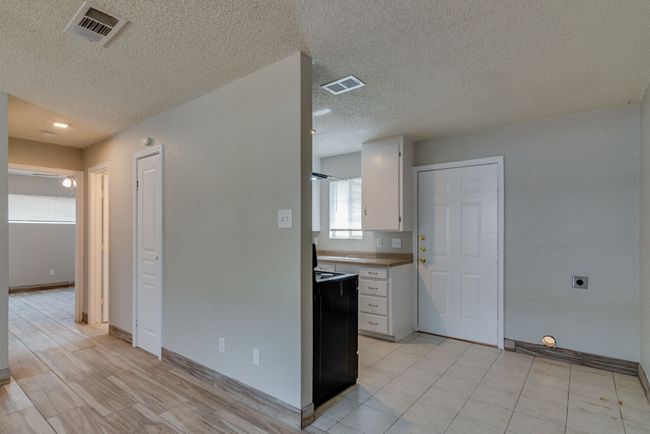 Kitchen with white cabinetry, visible vents, and a textured ceiling | Image 7