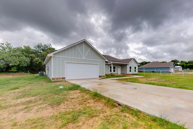 Ranch-style house featuring board and batten siding, an attached garage, and driveway | Image 11