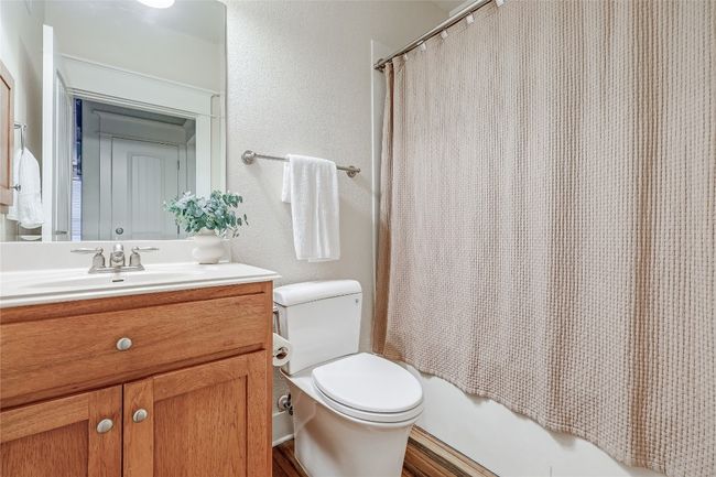 Bathroom featuring toilet, vanity, a textured wall, and shower / tub combo | Image 14
