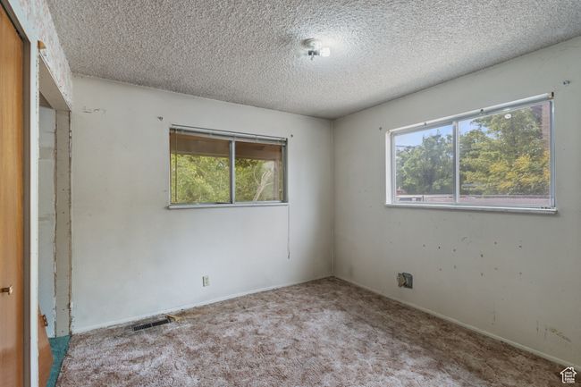 Unfurnished bedroom with a textured ceiling, carpet, and multiple windows | Image 22