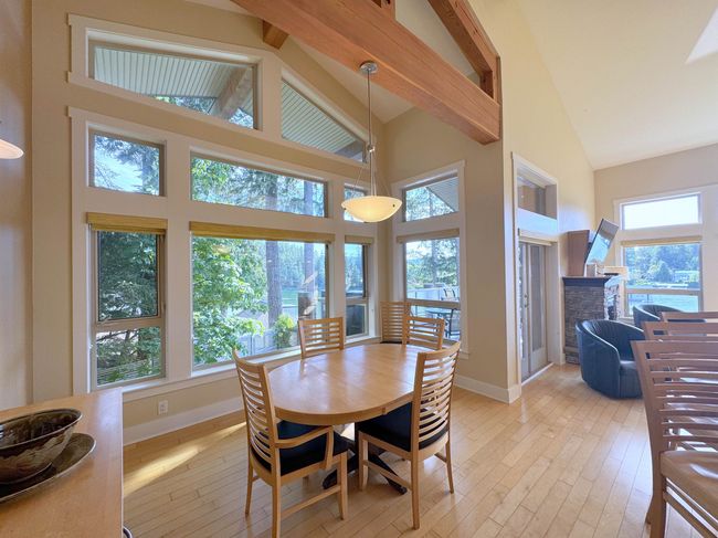 Dining room featuring high vaulted ceiling, light wood-type flooring, a stone fireplace, and beam ceiling | Image 13