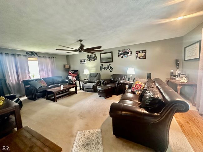 carpeted living room featuring a textured ceiling and ceiling fan | Image 22