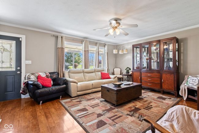 living room featuring crown molding, laminate finished floors, and ceiling fan | Image 8