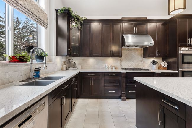 Kitchen with light stone counters, a sink, exhaust hood, appliances with stainless steel finishes, and tasteful backsplash | Image 12