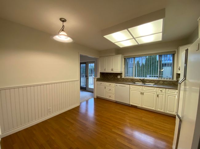 Kitchen featuring white appliances, a sink, dark wood-type flooring, dark countertops, and tasteful backsplash | Image 4