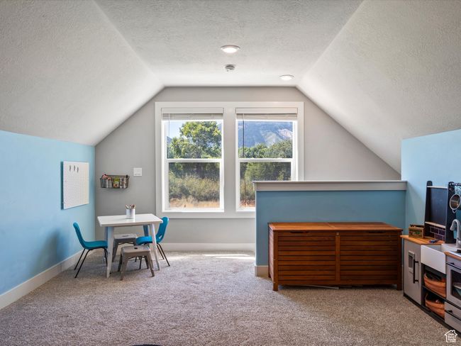 Rec room with vaulted ceiling, carpet flooring, a textured ceiling, and baseboards | Image 24