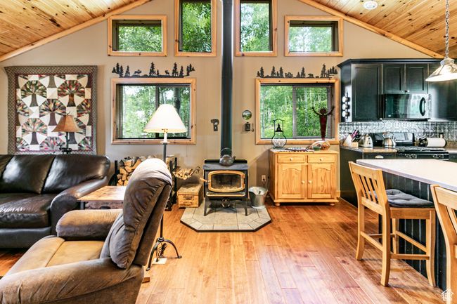 Living area with wood ceiling, a wood stove, light wood-style floors, plenty of natural light, and high vaulted ceiling | Image 16