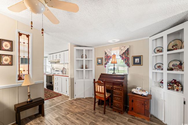 Office space featuring healthy amount of natural light, ceiling fan, light wood-type flooring, a textured ceiling, and a decorative wall | Image 19