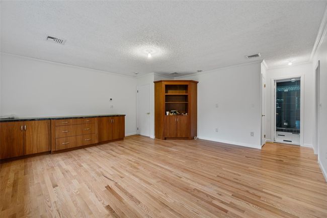 Unfurnished living room with light wood-type flooring, a textured ceiling, and crown molding | Image 16