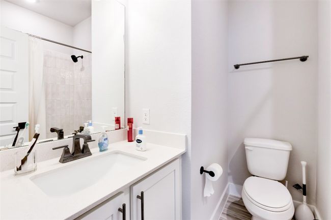 Bathroom with baseboards, toilet, a shower with shower curtain, and vanity | Image 10