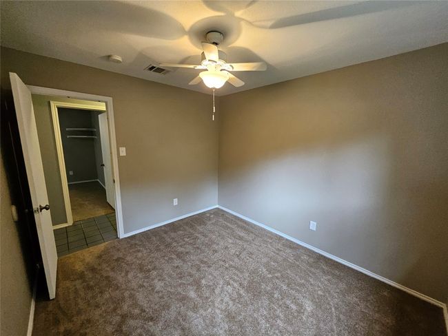Unfurnished bedroom with baseboards, ceiling fan, visible vents, a walk in closet, and carpet floors | Image 31