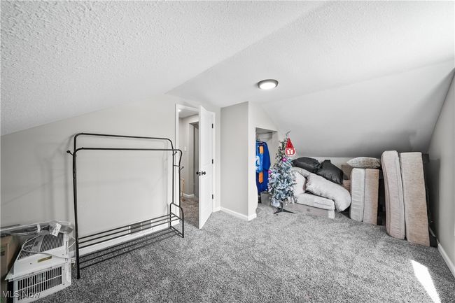 Additional living space featuring a textured ceiling, vaulted ceiling, carpet floors, and baseboards | Image 20