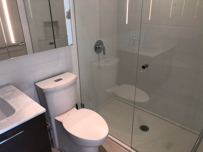 Full bathroom with toilet, vanity, a shower stall, and tile walls | Image 14