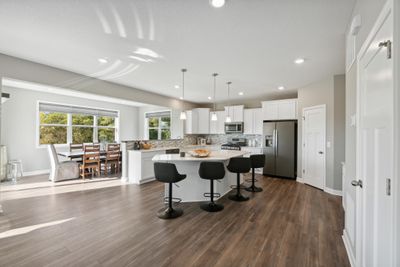 (Photo of a decorated model, actual homes finishes will vary) You will love your new kitchen. Enjoy a large center island, wonderful walk in pantry, state of the art SS appliances w/direct venting, quartz throughout the home! | Image 3