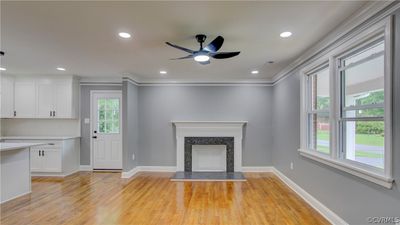 Unfurnished living room featuring ceiling fan, ornamental molding, light hardwood / wood-style flooring, and a fireplace | Image 3