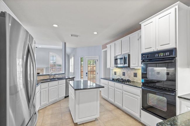 Featuring a center island, this kitchen offers extra storage and additional prep space. | Image 12