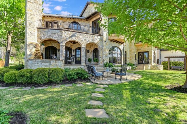 Rear view of property featuring stone siding, a balcony, french doors, and a lawn | Image 23