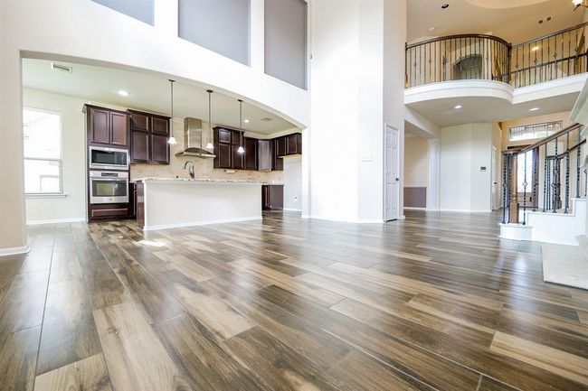 This view defines symmetry in a grand, yet warm presentation in this complete look from living and combined kitchen areas, up to the Juliet balcony-like railing, with a clear view, right, straight to the front door! | Image 9