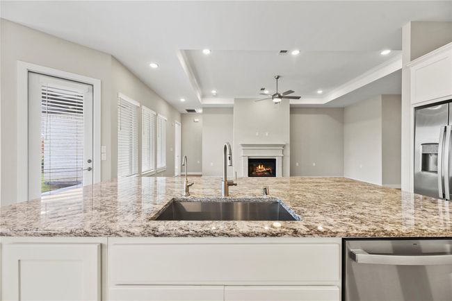 Cleanup is a breeze with the deep basin stainless steel sink, on-demand hot water, and built-in dishwasher, all while guests relax at the bar and keep you company. Enjoy conversation and a view of the cozy fireplace as you tidy up. | Image 18
