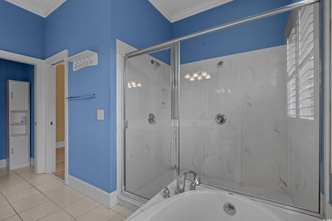 Bathroom featuring a marble finish shower, a bath, ornamental molding, and tile patterned floors | Image 22