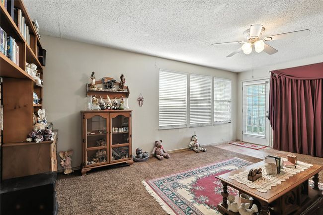 Carpeted living room featuring a ceiling fan and a textured ceiling | Image 23