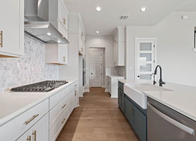 Kitchen featuring a sink, stainless steel appliances, wall chimney exhaust hood, visible vents, and white cabinets | Image 13