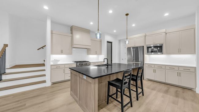 Kitchen with appliances with stainless steel finishes, a sink, premium range hood, decorative backsplash, and a kitchen breakfast bar | Image 19