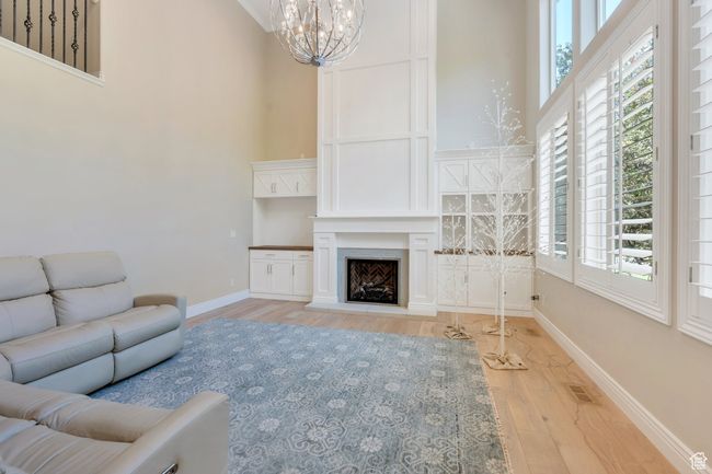 Living area with a high ceiling, a chandelier, wood finished floors, healthy amount of natural light, and baseboards | Image 9